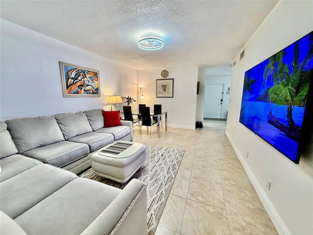 living area featuring baseboards, visible vents, and a textured ceiling