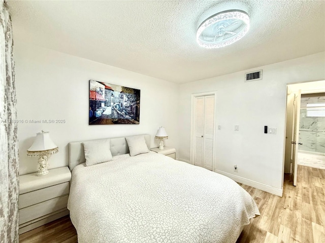 bedroom with baseboards, visible vents, a closet, a textured ceiling, and light wood-type flooring