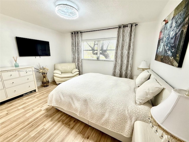 bedroom featuring light wood finished floors and a textured ceiling