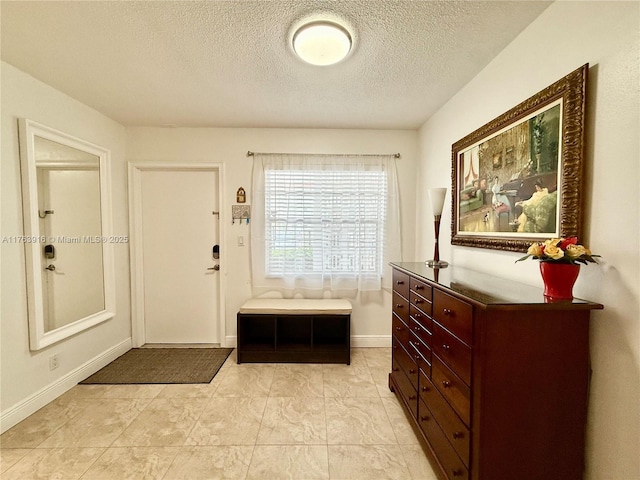 foyer entrance featuring a textured ceiling and baseboards