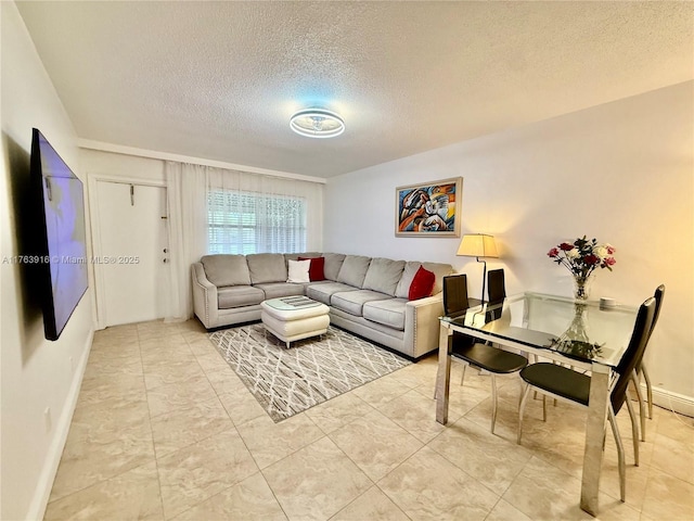 living area featuring a textured ceiling and baseboards