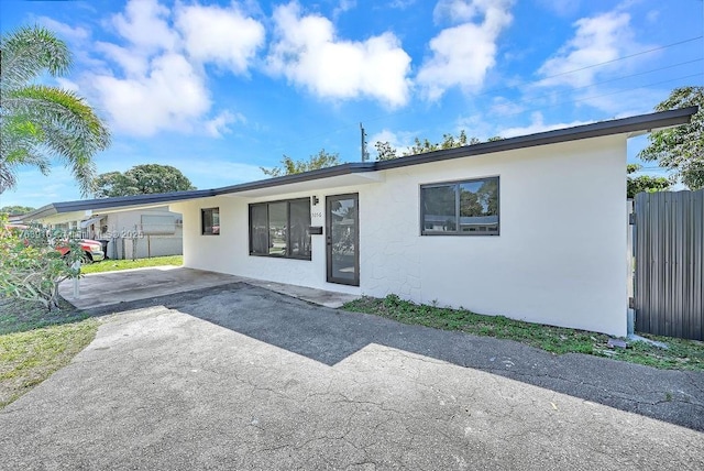 single story home with a carport, stucco siding, driveway, and fence