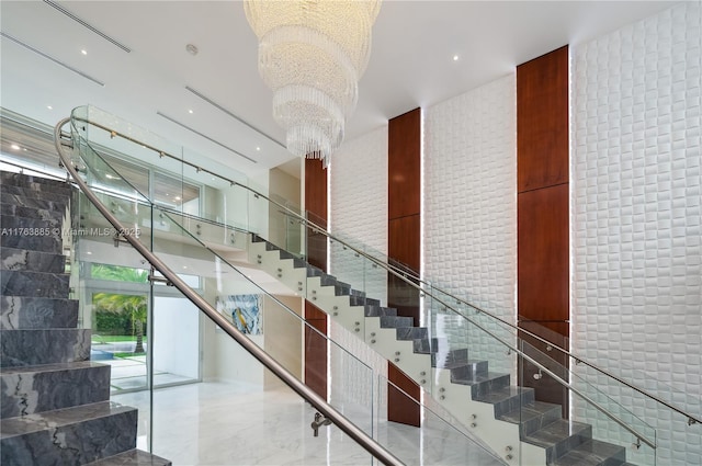 stairway with expansive windows, marble finish floor, and a chandelier