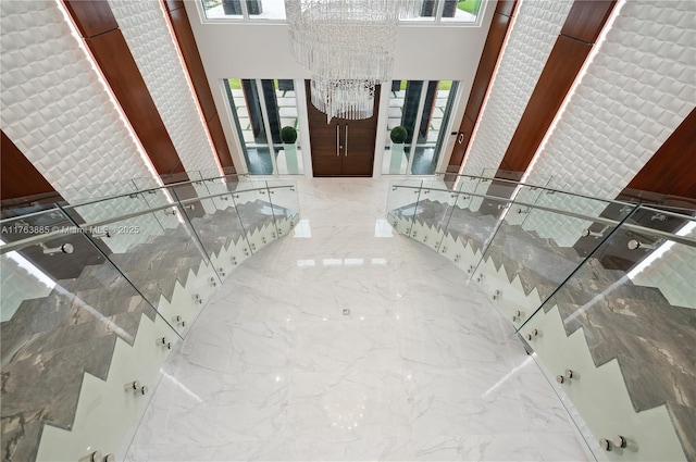 interior space with a chandelier, marble finish floor, and a towering ceiling