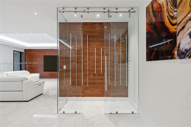 hallway featuring a raised ceiling and marble finish floor