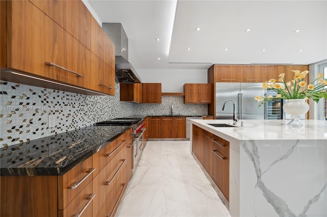 kitchen featuring stainless steel built in fridge, brown cabinets, marble finish floor, modern cabinets, and wall chimney exhaust hood