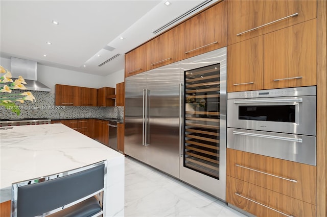 kitchen featuring appliances with stainless steel finishes, marble finish floor, modern cabinets, wall chimney exhaust hood, and a warming drawer