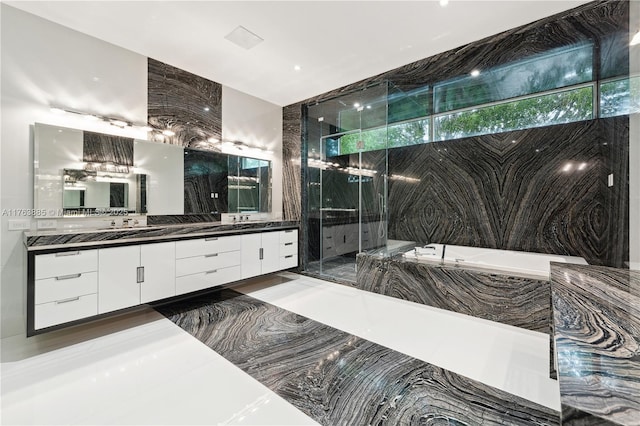 bathroom with a marble finish shower, a bath, and vanity