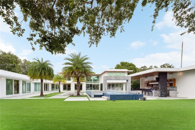 rear view of property featuring a patio area, a lawn, and stucco siding