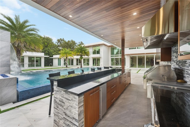 view of patio featuring an exterior structure, an infinity pool, an outdoor structure, and exterior kitchen