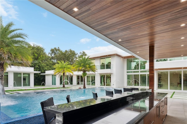 pool featuring outdoor wet bar, a patio, and an outbuilding