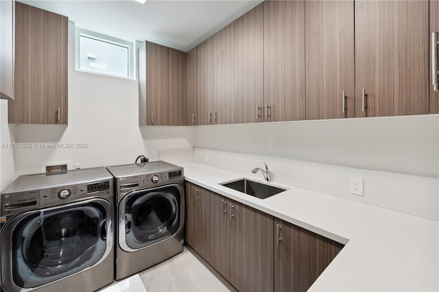 laundry area featuring washer and dryer, cabinet space, and a sink