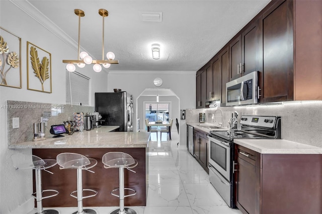 kitchen featuring ornamental molding, marble finish floor, appliances with stainless steel finishes, and a sink