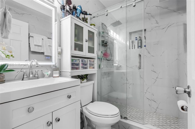 full bathroom with a marble finish shower, toilet, and vanity