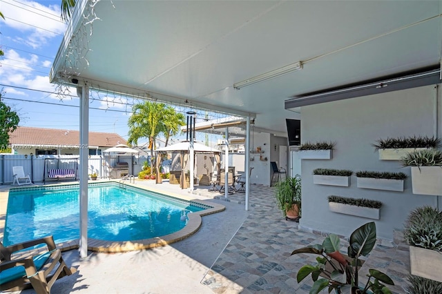 view of pool with a gazebo, a fenced backyard, a fenced in pool, and a patio