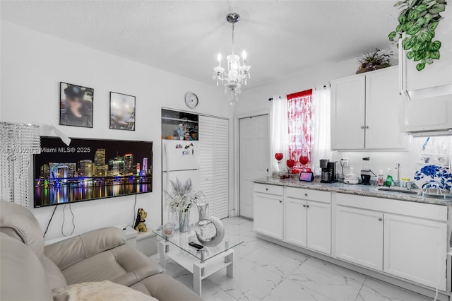 living room with a notable chandelier, marble finish floor, and a textured ceiling