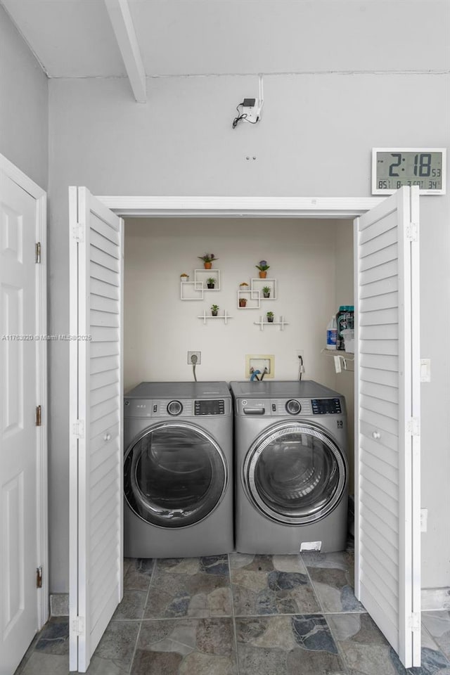 washroom featuring washing machine and dryer, laundry area, and stone finish floor