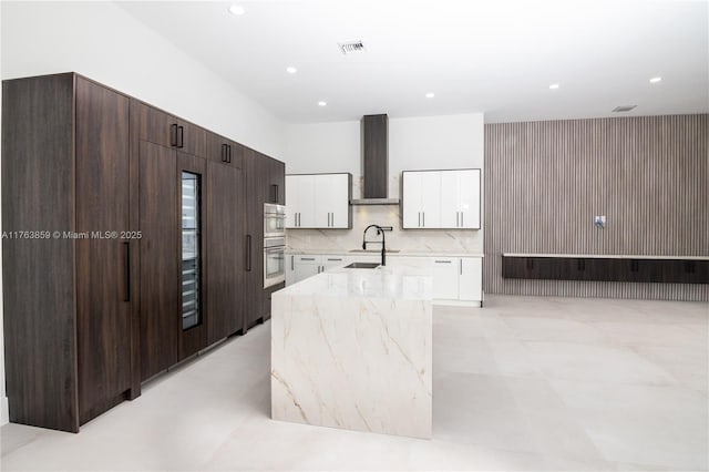 kitchen featuring a sink, modern cabinets, wall chimney exhaust hood, and white cabinetry