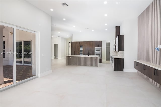 kitchen featuring dark brown cabinetry, tasteful backsplash, modern cabinets, and visible vents