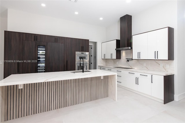 kitchen featuring modern cabinets, a sink, stainless steel double oven, wall chimney exhaust hood, and black electric cooktop