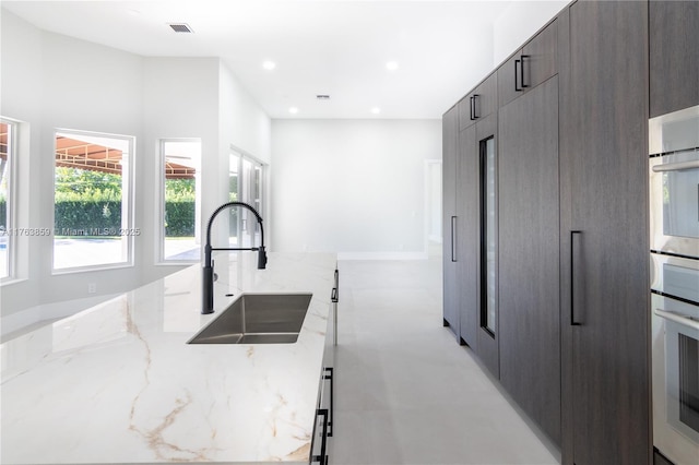 kitchen with light stone counters, visible vents, recessed lighting, a sink, and modern cabinets