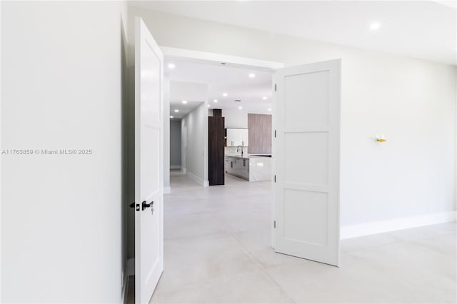 hall featuring recessed lighting, baseboards, and a sink