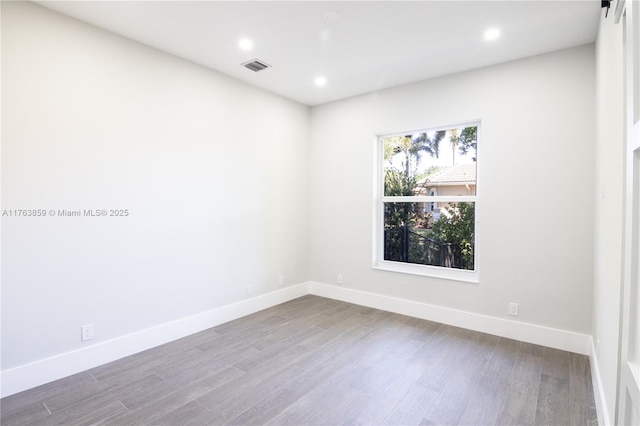 unfurnished room with recessed lighting, wood finished floors, visible vents, and baseboards