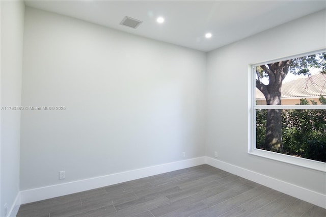 spare room with baseboards, plenty of natural light, and wood finished floors