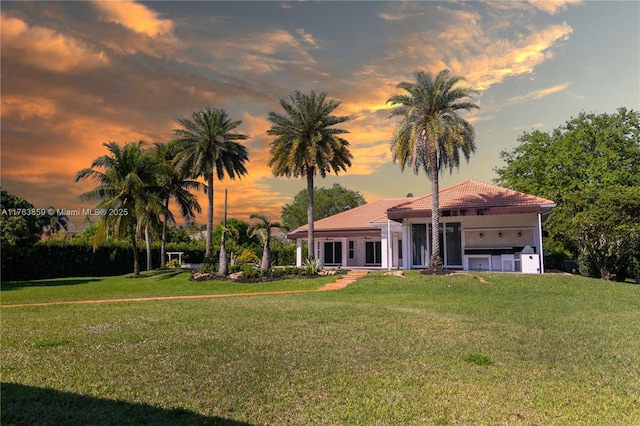 mediterranean / spanish house with a tile roof, a front yard, and stucco siding