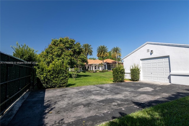 exterior space featuring aphalt driveway, fence, and a garage