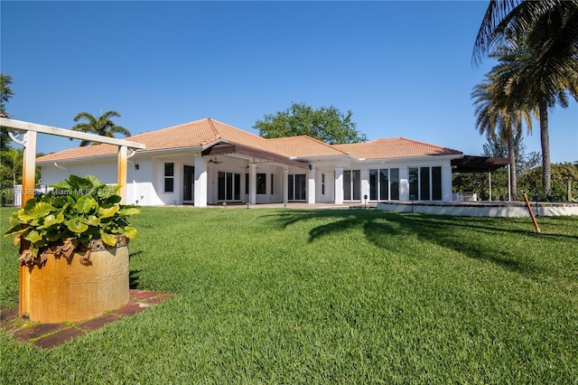 back of property featuring stucco siding, ceiling fan, a tiled roof, a patio area, and a lawn