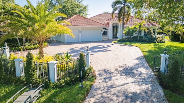 mediterranean / spanish home featuring a fenced front yard, a tiled roof, and decorative driveway