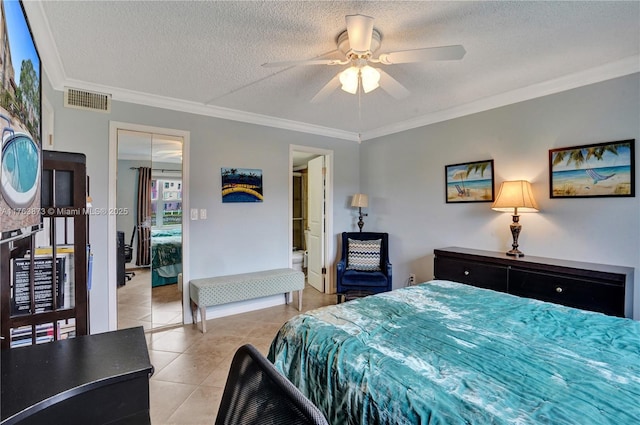 bedroom with a textured ceiling, light tile patterned floors, visible vents, and ornamental molding