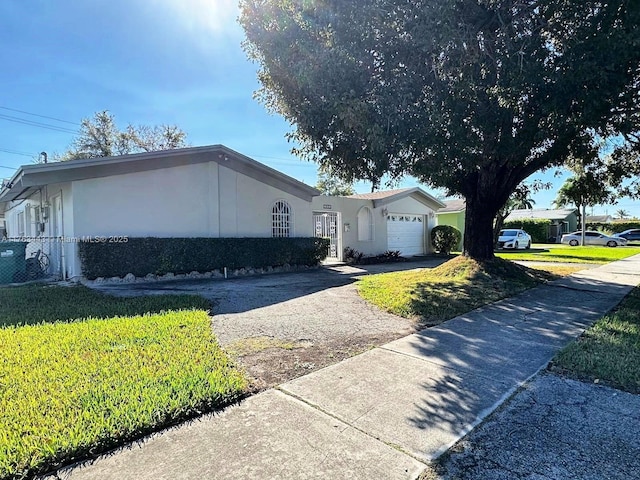 single story home featuring concrete driveway, an attached garage, a front lawn, and stucco siding