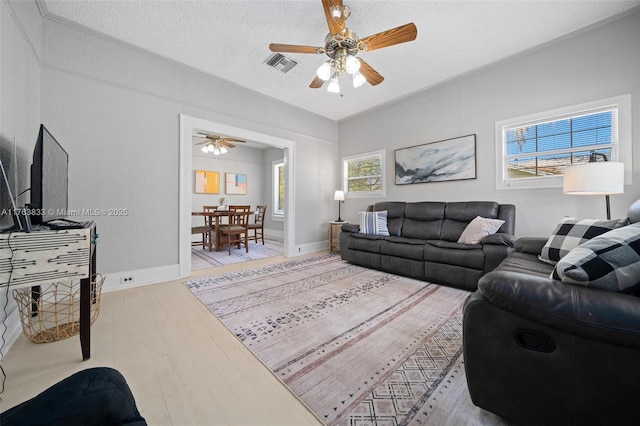 living room featuring visible vents, a textured ceiling, light wood-style floors, and a ceiling fan