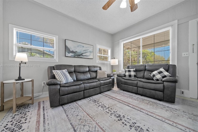 living room featuring baseboards, a textured ceiling, and ceiling fan