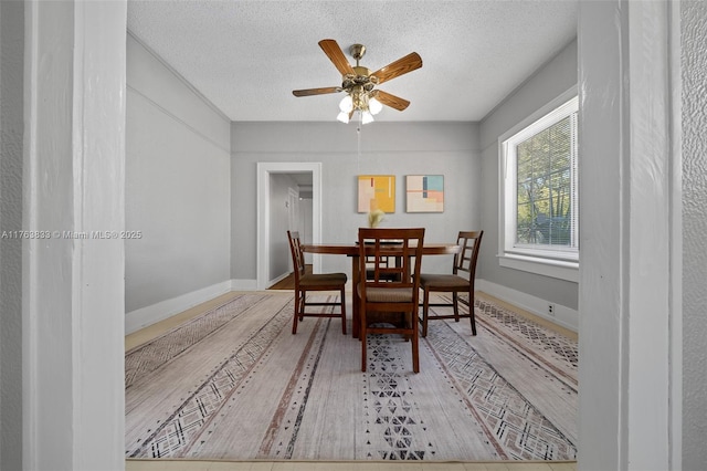 dining room featuring baseboards, a textured ceiling, a ceiling fan, and wood finished floors