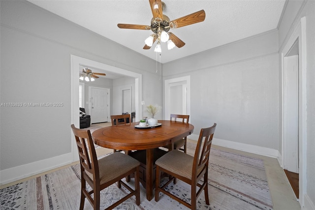 dining space with a textured ceiling, baseboards, and ceiling fan