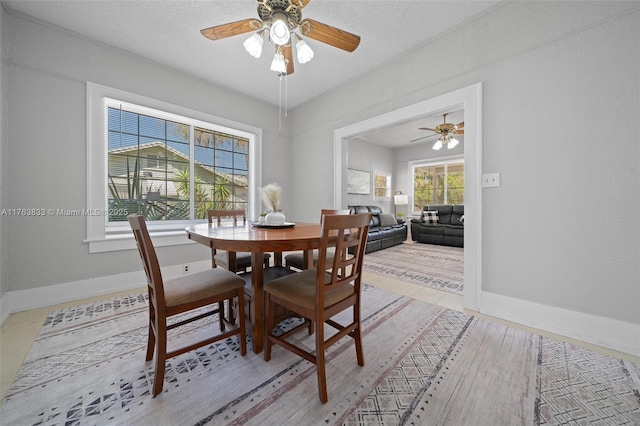 dining room featuring baseboards, a textured ceiling, ceiling fan, and a textured wall