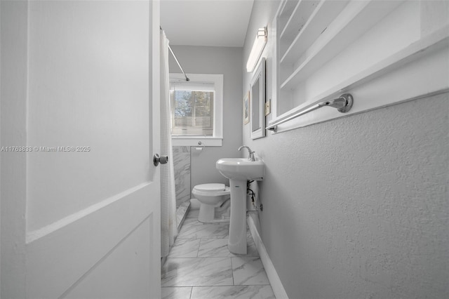 full bathroom featuring toilet, baseboards, marble finish floor, and walk in shower