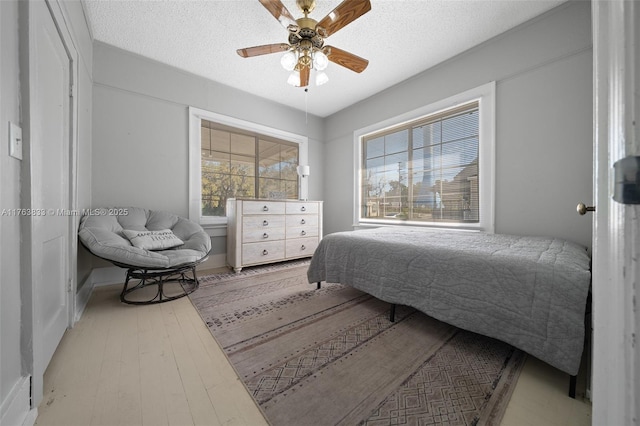 bedroom with ceiling fan, a textured ceiling, and wood finished floors