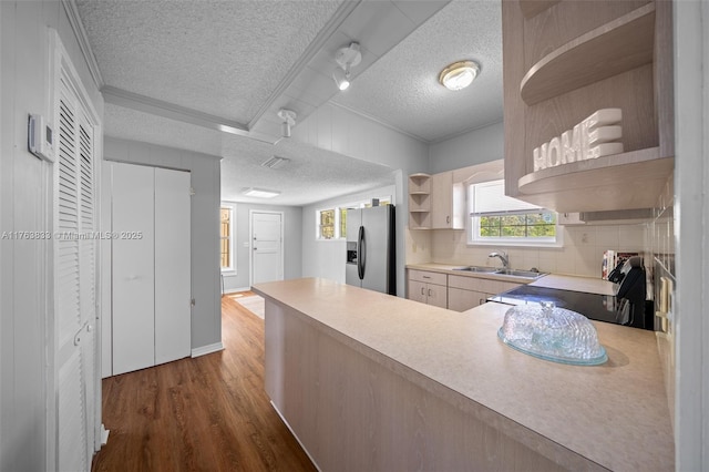 kitchen with open shelves, stainless steel refrigerator with ice dispenser, wood finished floors, stove, and a sink