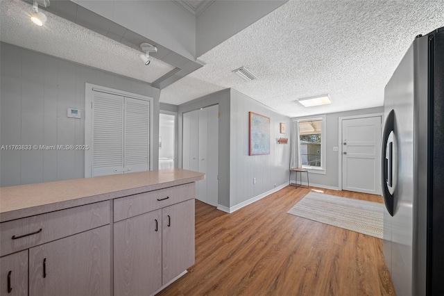 kitchen with visible vents, a textured ceiling, wood finished floors, freestanding refrigerator, and light countertops