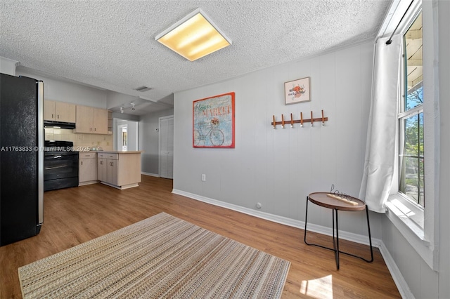 kitchen featuring wood finished floors, electric range, freestanding refrigerator, light countertops, and under cabinet range hood