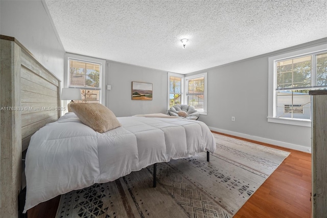 bedroom with wood finished floors, baseboards, and a textured ceiling