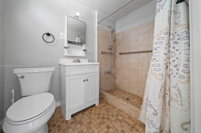 bathroom featuring baseboards, toilet, vanity, and a tile shower