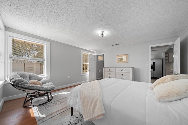 bedroom with visible vents, multiple windows, baseboards, and wood finished floors