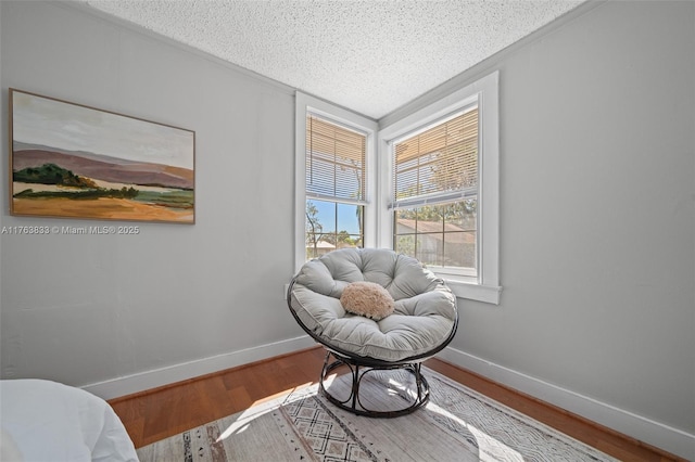 sitting room featuring baseboards, a textured ceiling, and wood finished floors