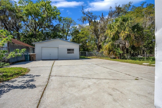 garage with concrete driveway and fence