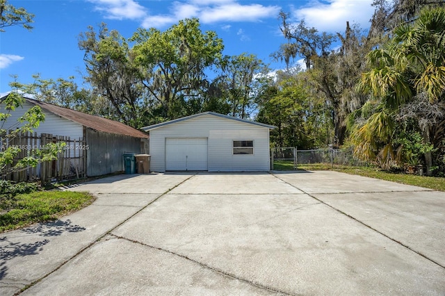 garage featuring concrete driveway and fence